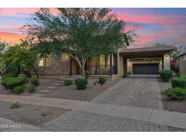 Charming single-story home with stone accents, mature landscaping, and a covered carport at sunset at 17727 N 95Th Pl, Scottsdale, AZ 85255