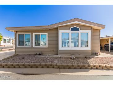 Charming single-story home featuring light brown siding and decorative rock landscaping at 5735 E Mcdowell E Rd # 213, Mesa, AZ 85215