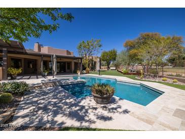 Backyard swimming pool and patio area with outdoor seating under blue sky at 8233 E Foothill Cir, Scottsdale, AZ 85255