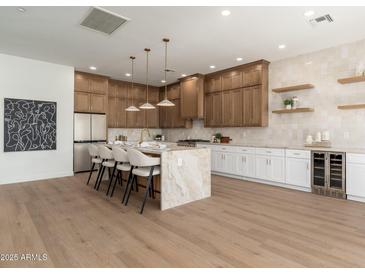 Modern kitchen island bar with pendant lights, updated stainless appliances and sleek countertops at 11267 E Beck Ln, Scottsdale, AZ 85255