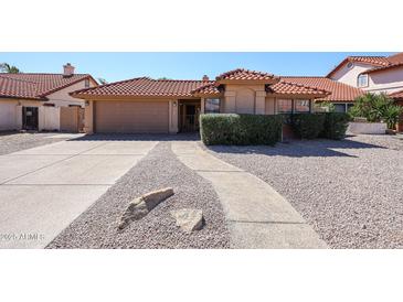Charming single-story home with a red tile roof, a two car garage and desert landscaping at 1833 E Redfield Rd, Phoenix, AZ 85022