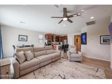 Open-concept living room with tile flooring, ceiling fan, and views into the kitchen and dining area at 26955 W Adam Ave, Buckeye, AZ 85396