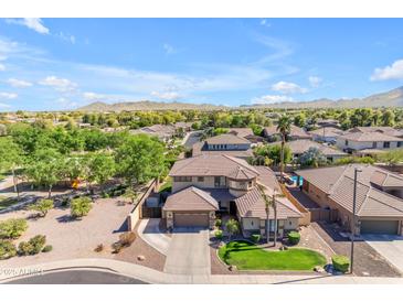 Expansive aerial view of a home with a tiled roof, a pool, and mountain views in the distance, showing the neighborhood at 4455 E Palmdale Ln, Gilbert, AZ 85298