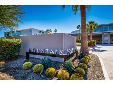 The community entrance features desert plants and cacti surrounding a modern sign with a building in the background at 5455 E Lincoln Dr # 3008, Paradise Valley, AZ 85253