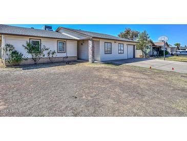 Single-Gathering home with tan siding, a brick pillar, and an attached garage on a sunny day at 6025 W Marconi Ave, Glendale, AZ 85306