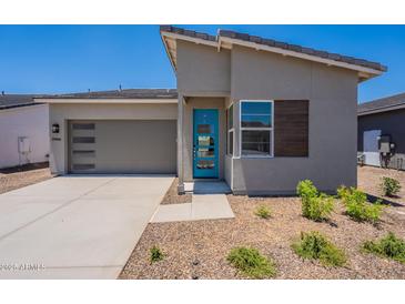 Attractive single Gathering home showcasing desert landscaping, a gray garage door, and a bright blue front door at 17966 W Long Lake Rd, Goodyear, AZ 85338