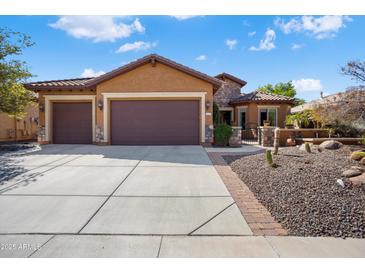 Charming single-story home with a well-manicured yard and three-car garage under a blue sky at 26293 W Runion Ln, Buckeye, AZ 85396