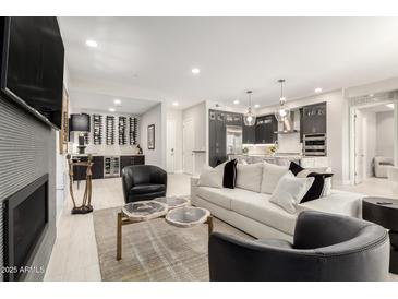 Open-concept living room featuring modern furnishings, a fireplace, a sleek bar, and an adjacent kitchen at 5250 E Deer Valley Dr # 146, Phoenix, AZ 85054