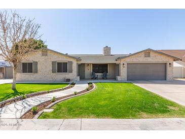 Charming home featuring a lush front lawn, stone accents, shutters, and a welcoming two-car garage at 5333 E Catalina Ave, Mesa, AZ 85206