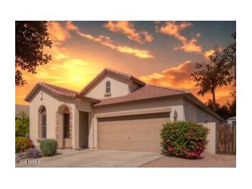 Inviting single-story home with a two-car garage, lush landscaping, and a warm, welcoming sunset backdrop at 6279 S Martingale Ct, Gilbert, AZ 85298