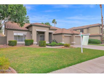 Inviting single-Gathering home featuring a well-manicured lawn and a symmetrical design, complemented by a tile roof and desert landscaping at 6793 W Angela Dr, Glendale, AZ 85308