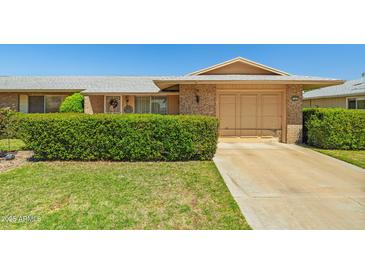 Charming brick home with a well-maintained lawn and mature landscaping at 11012 W Caron Dr, Sun City, AZ 85351
