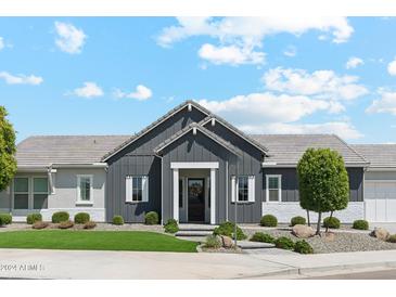 Inviting home featuring dark gray exterior paint, a well-manicured lawn, and a beautiful, landscaped yard at 17332 W Wildwood St, Surprise, AZ 85388
