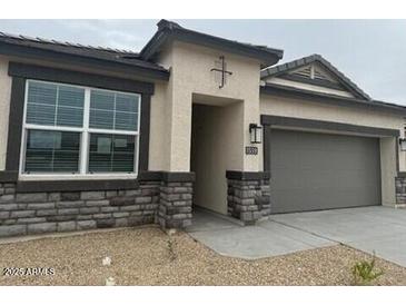 Charming one-story home with stone accents, a gray two-car garage door, and a well-kept front yard at 23972 W Cocopah St, Buckeye, AZ 85326