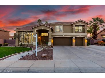 Beautiful two-story home with a well-manicured lawn, three-car garage and mature palm trees at sunset at 4812 S Windstream Pl, Chandler, AZ 85249