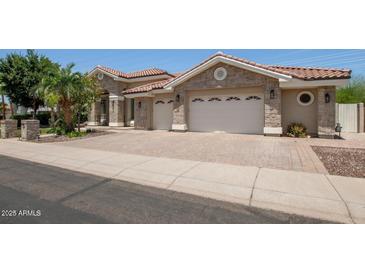 Beautiful home features a paver driveway, stone accents, lush landscaping, and a tile roof at 11054 E North Ln, Scottsdale, AZ 85259