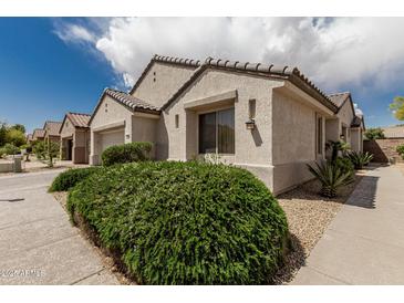Charming home with a light stucco exterior, tile roof, and lush landscaping at 15885 W Remington Dr, Surprise, AZ 85374