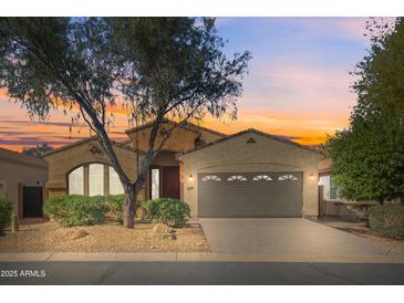 Charming home with a two-car garage, desert landscaping, and a colorful sky at sunset at 18222 E La Posada Ct, Gold Canyon, AZ 85118