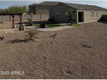 Large backyard with gravel landscaping, a pergola, and green grass, offering a versatile outdoor living space at 29908 W Monterey Dr, Buckeye, AZ 85396