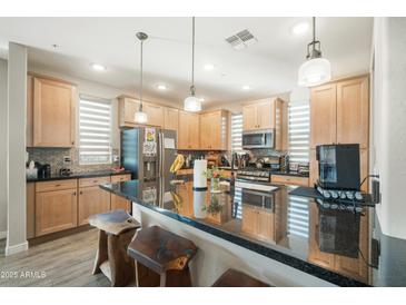 Modern kitchen with wooden cabinets, granite countertops, and a large island with stylish wood stools at 5100 E Rancho Paloma E Dr # 1046, Cave Creek, AZ 85331