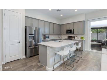 Modern kitchen with stainless steel appliances, gray cabinets, an island with bar seating and pendant lights at 3045 N 37Th Way, Phoenix, AZ 85018