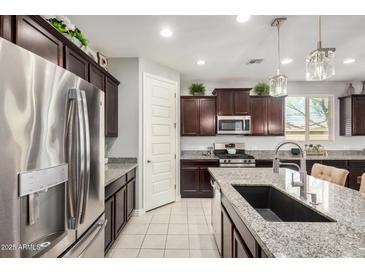 Well-equipped kitchen featuring stainless steel appliances, granite countertops, dark wood cabinets, and large island at 10454 W Maya Way, Peoria, AZ 85383