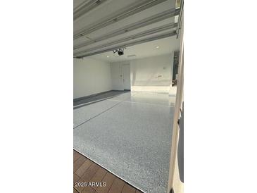 Spacious two-car garage featuring painted walls and epoxy-coated flooring for a clean and modern look at 25727 N 147Th Dr, Surprise, AZ 85387