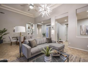 Inviting living room featuring a modern gray sofa, striking light fixture, and elegant decor at 33601 N 64Th St, Scottsdale, AZ 85266