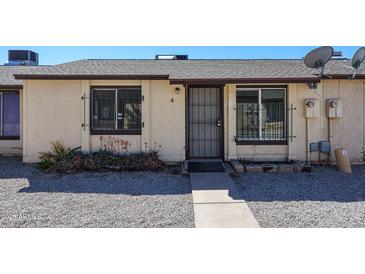 Exterior of a tan home featuring a security door, rock landscaping, and window bars at 3646 N 69Th Ave # 4, Phoenix, AZ 85033