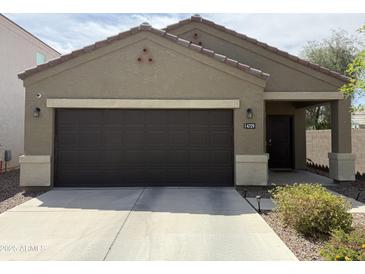 Single-story home featuring a two-car garage with a dark brown door and desert landscaping at 4729 E Chromium Rd, San Tan Valley, AZ 85143