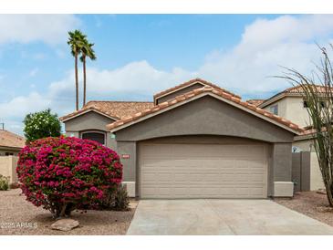 Charming single-Gathering home featuring desert landscaping, a two-car garage and a tile roof at 6014 E Sayan Cir, Mesa, AZ 85215