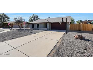 Charming single-story home with a gray rock yard, a long concrete driveway, and an attached two-car garage at 6029 W Pershing Ave, Glendale, AZ 85304