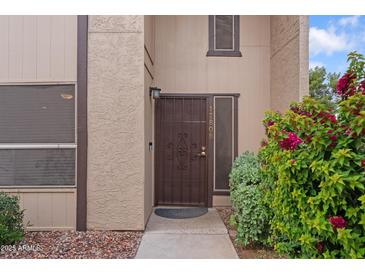 Inviting front entrance features a secure metal door and lush, colorful landscaping around the walkway at 17808 N 45Th Ave, Glendale, AZ 85308