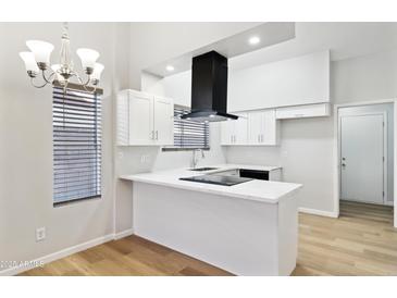 Bright kitchen features white cabinetry, modern black vent hood, and island with white countertop at 3326 E Calypso Ave, Mesa, AZ 85204