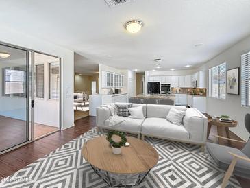 Spacious living room flowing into the kitchen, with a large sofa, stylish rug, and ample natural light at 14437 W Lexington Ave, Goodyear, AZ 85395