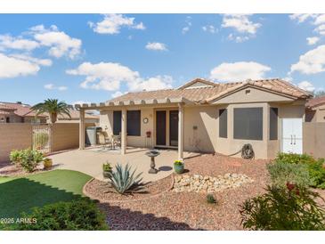 Well-maintained backyard featuring a covered patio, desert landscaping, and artificial turf area at 16160 W Starlight Dr, Surprise, AZ 85374