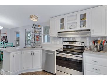 Well-lit kitchen featuring white cabinetry, stainless steel appliances, and modern fixtures at 201 S Greenfield Rd # 255, Mesa, AZ 85206