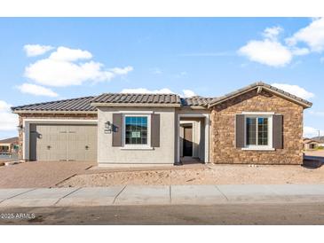 Charming single-story home featuring a stone facade, tan shutters, and a two-car garage at 26930 W Renee Dr, Buckeye, AZ 85396
