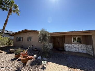 Charming single-story home with desert landscaping and stone accents, complemented by a lush palm tree in the front yard at 5829 E Windsor Ave, Scottsdale, AZ 85257