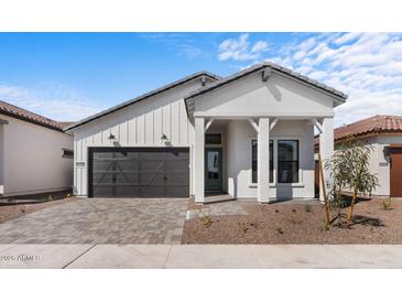 Charming single-story home with modern farmhouse design, paver driveway and dark garage door at 20308 W Montecito Ave, Buckeye, AZ 85396