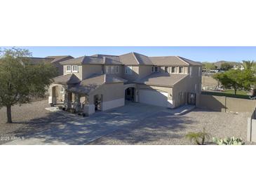 View of a beige two-story home featuring a tile roof, an attached two-car garage, and a well-maintained front yard at 31918 N Caspian Way, San Tan Valley, AZ 85143