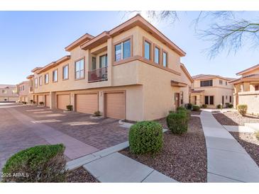 View of townhomes featuring private garages, patios, and well-maintained landscaping in a sunny neighborhood at 42424 N Gavilan Peak Pkwy # 63212, Anthem, AZ 85086