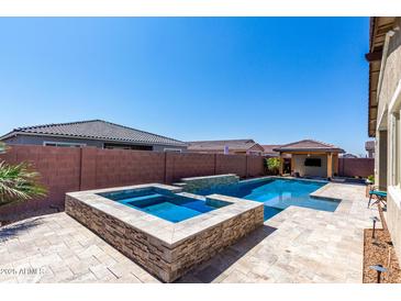 Beautiful pool with a built-in spa, and a covered outdoor living area in the backyard at 45975 W Mountain View Rd, Maricopa, AZ 85139