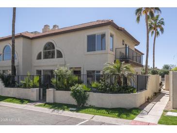 Inviting two-story stucco home with a tile roof, lush landscaping, and a charming wrought iron fenced in patio at 4927 E Hazel Dr # 2, Phoenix, AZ 85044