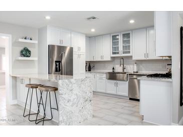 Bright kitchen with granite counters, stainless steel appliances, island with seating, and white cabinetry at 8408 E Lewis Ave, Scottsdale, AZ 85257