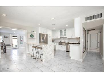 Bright kitchen with granite counters, stainless steel appliances, island with seating, and white cabinetry at 8408 E Lewis Ave, Scottsdale, AZ 85257