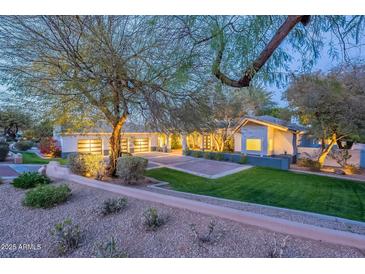 Stunning home exterior with a lush, landscaped yard and multi-car garage, illuminated at dusk at 9041 N 46Th St, Phoenix, AZ 85028