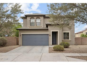 Charming two-story home featuring a gray garage door, desert landscaping and arched second story windows at 15758 W Cortez St, Surprise, AZ 85379
