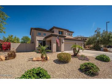 Beautiful home with desert landscaping, neutral tones, an American flag, and well-manicured bushes at 3547 N 145Th Ave, Goodyear, AZ 85395