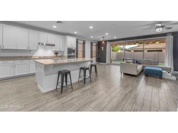 Modern kitchen with white cabinets, granite countertops, and stainless steel appliances open to the living area at 3938 E Ficus Way, Gilbert, AZ 85298